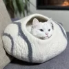 hvit kattehule med grå striper med en katt som koser seg inne i kattehulen